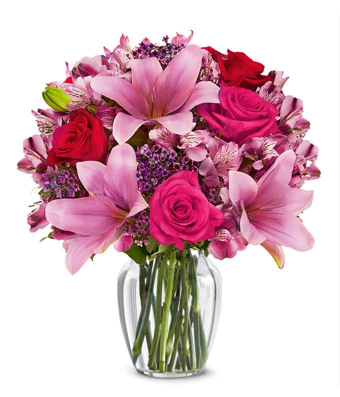 A beautiful arrangement featuring pink Asiatic lilies, pink and red roses, and alstroemeria, optionally arranged in a glass vase. This elegant mix offers a lovely and vibrant display