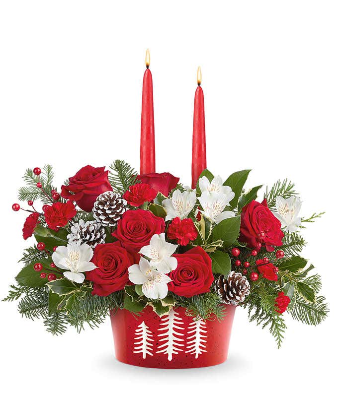 Holiday bouquet with red roses, white alstroemeria, and miniature red carnations in a polar bear mug with festive greenery and red-and-white striped ribbon.