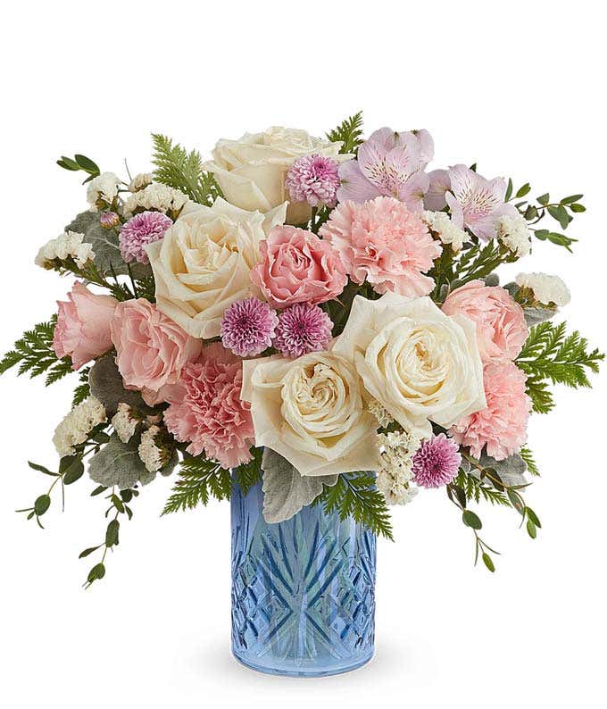 White Roses, Pink Spray Roses, Lavender Alstroemeria, Pink Carnations, Lavender Button Poms, and Floral Greenery in a Blue Cylinder Vase with Dart Deco Design