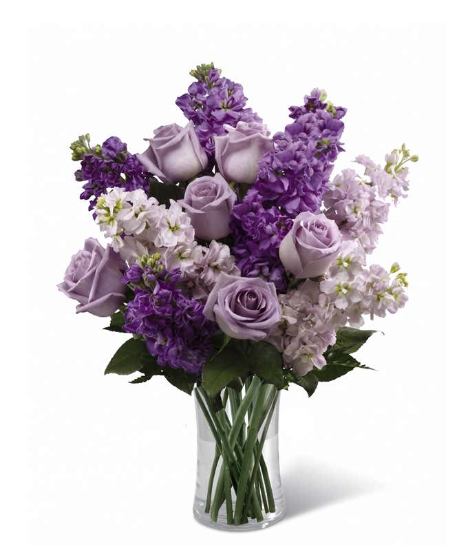 Purple roses and stock in glass vase