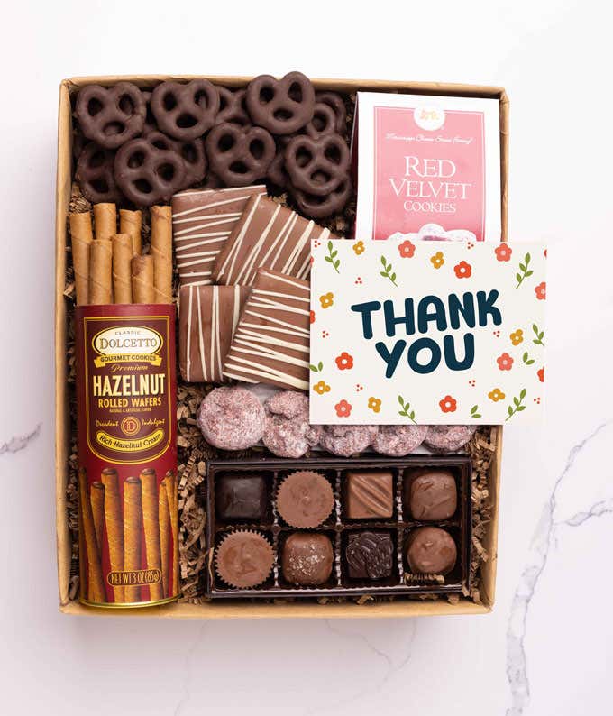 A gift box with chocolate pretzels, chocolate graham crackers, red velvet cookies, hazelnut wafer rolls, an 8 piece box of chocolates and a Thank You message card.