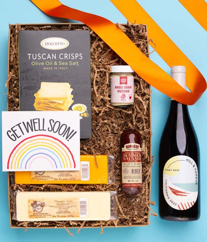 A gift box with a bottle of California Pinot Noir, two types of cheese, crackers, stone-ground mustard, a summer sausage and a Get Well Soon message card.