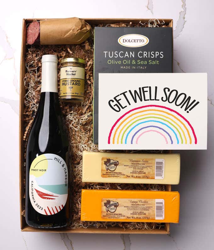 A gift box with a bottle of California Chardonnay, two types of cheese, crackers, stone-ground mustard, a summer sausage, and a Get Well Soon message card.