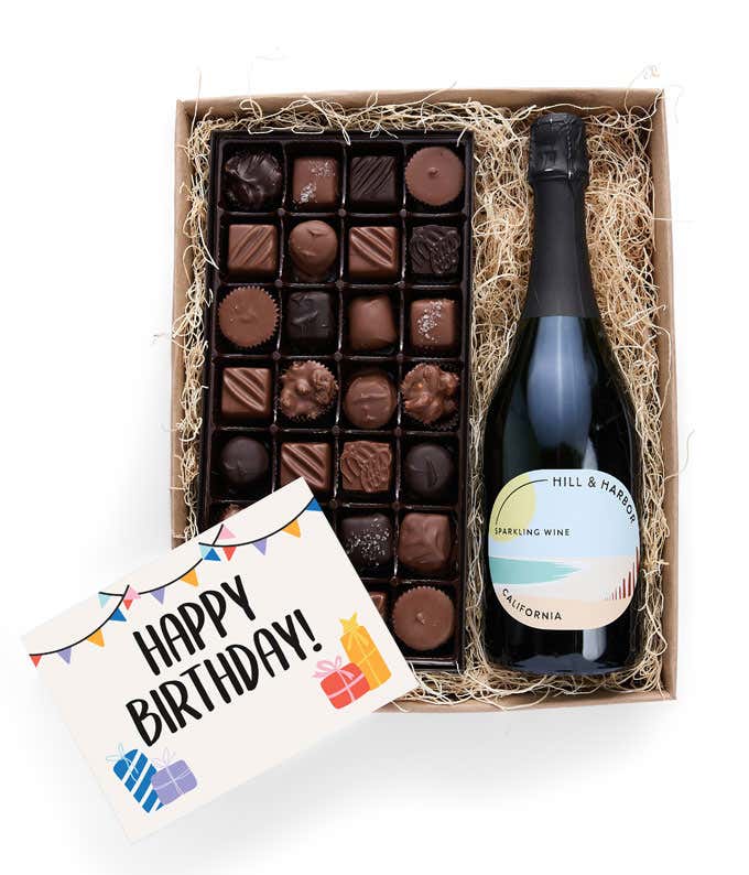 A birthday gift box containing a bottle of Hill & Harbor Sparkling Wine, a 1 lb box of 28 assorted gourmet chocolates in a grid, and a birthday message card.   A refined combination perfect for birthday celebrations.