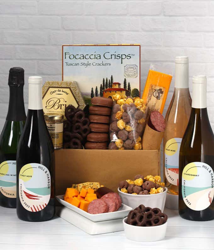 A gift set with 4 bottles of California wines - red, white, and sparkling, focaccia crisps, 2 cheeses, mustard, summer sausage, caramel popcorn, chocolate pretzels, and 6 chocolate-covered Oreos for a sweet and savory gourmet experience.