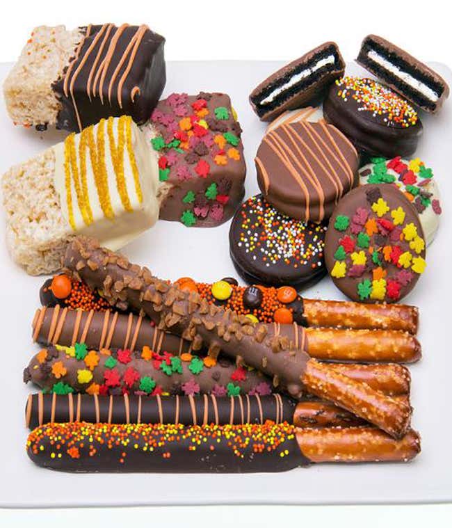 A delicious assortment featuring chocolate-covered rice treats, chocolate-covered OREO&reg; cookies, and chocolate-covered pretzels, all adorned with fall-themed edible decorations and coated in dark, white, and milk chocolate.