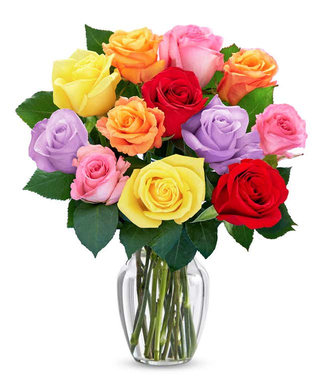 A bouquet of multicolored roses in a clear vase, featuring red, pink, orange, yellow, peach, and lavender blooms, arranged with green leaves for a vibrant and cheerful display.
