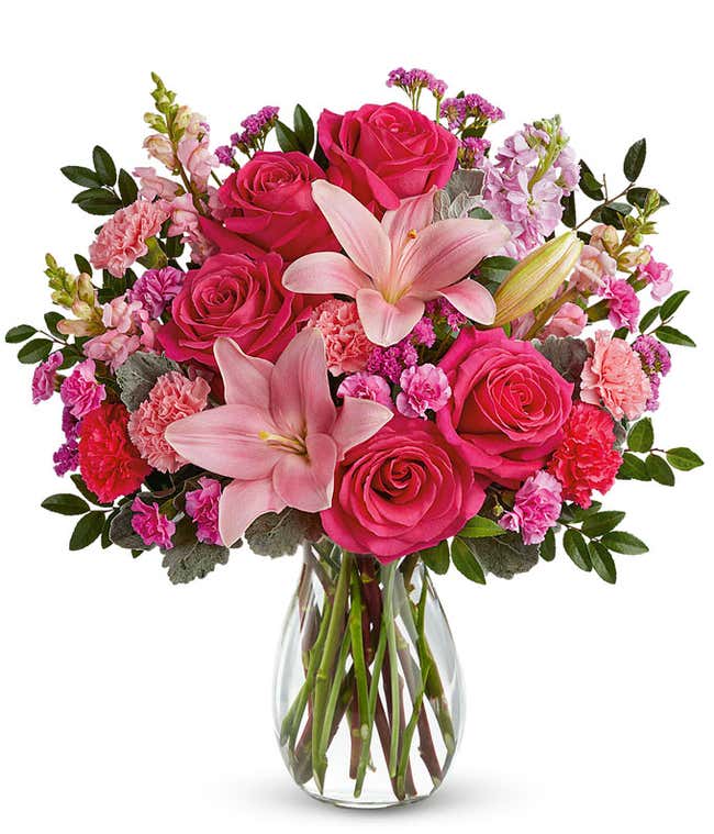 Image of a Mother's Day arrangement featuring Hot Pink Roses, Pink Asiatic Lilies, Light Pink Carnations, Hot Pink Carnations, Miniature Hot Pink Carnations, Pink Snapdragons, Light Pink Stock, Raspberry Sinuata Statice, all beautifully presented in a kee