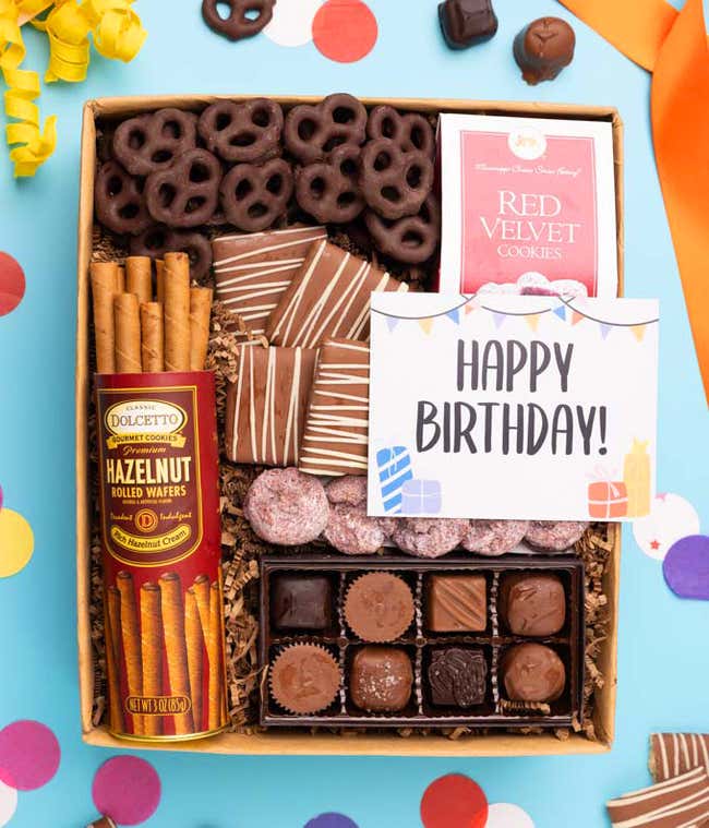 A gift box with chocolate pretzels, chocolate graham crackers, red velvet cookies, hazelnut wafer rolls, an 8 piece box of chocolates and a Season's Greeting message card.
