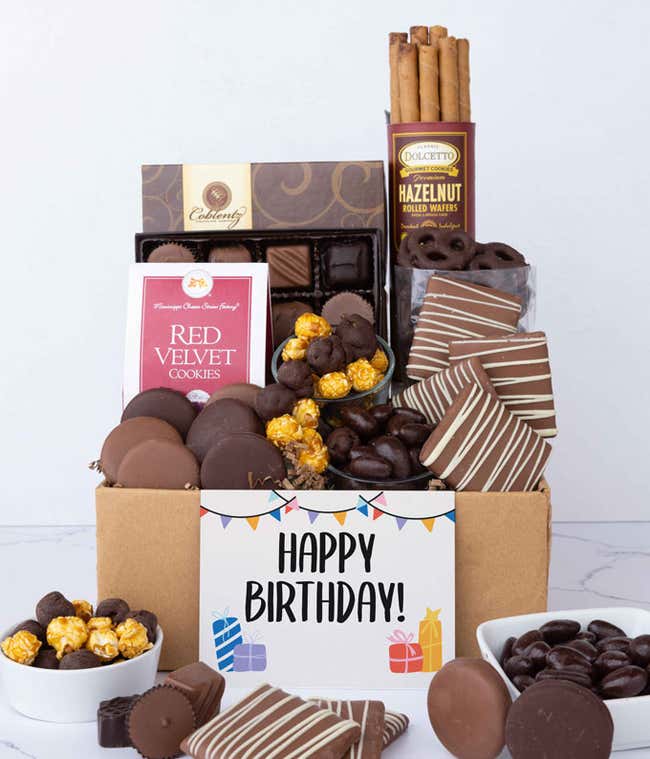 A gift box overflowing with treats including an assortment of chocolate-covered items like Oreos, almonds, graham crackers and pretzels along with red velvet cookies, hazelnut wafers, an 8-piece box of chocolates and a Birthday card.
