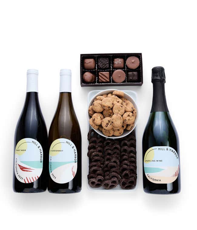 A gift box with chocolate pretzels, chocolate graham crackers, red velvet cookies, hazelnut wafer rolls, an 8 piece box of chocolates and 3 bottles of wine.