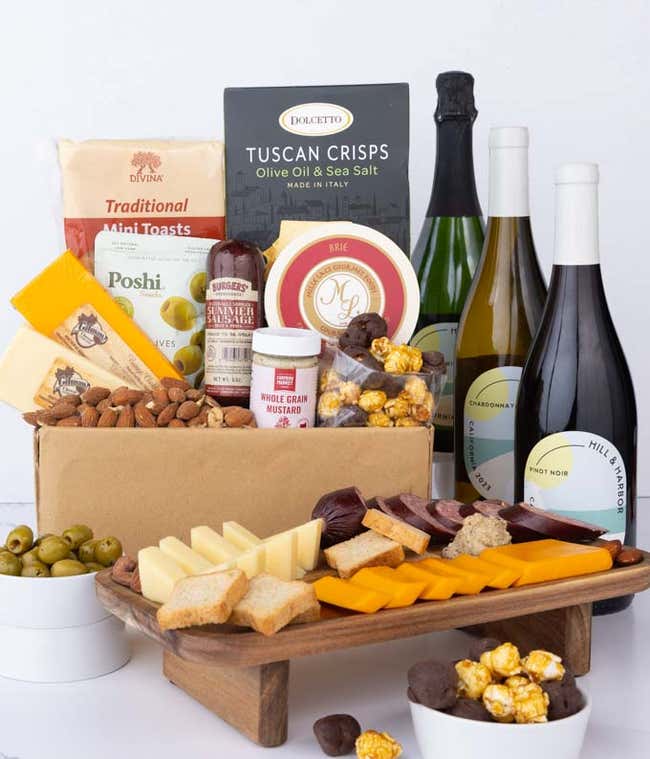 A wine and cheese gift set featuring bottles of Hill &amp; Harbor Sparkling wine, Chardonnay, and Pinot Noir. Includes a variety of cheeses, crackers, olives, roasted almonds, summer sausage, and condiments.
