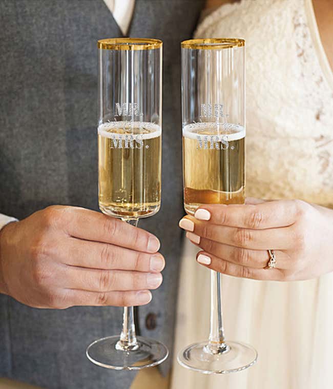 A tall champagne flute with a gold rim is engraved with Mr. &amp; Mrs.